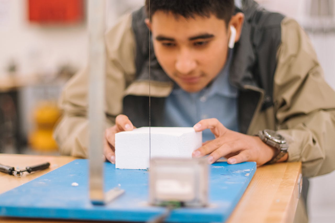 Student intensely concentrating on a workshop project with precision tools.